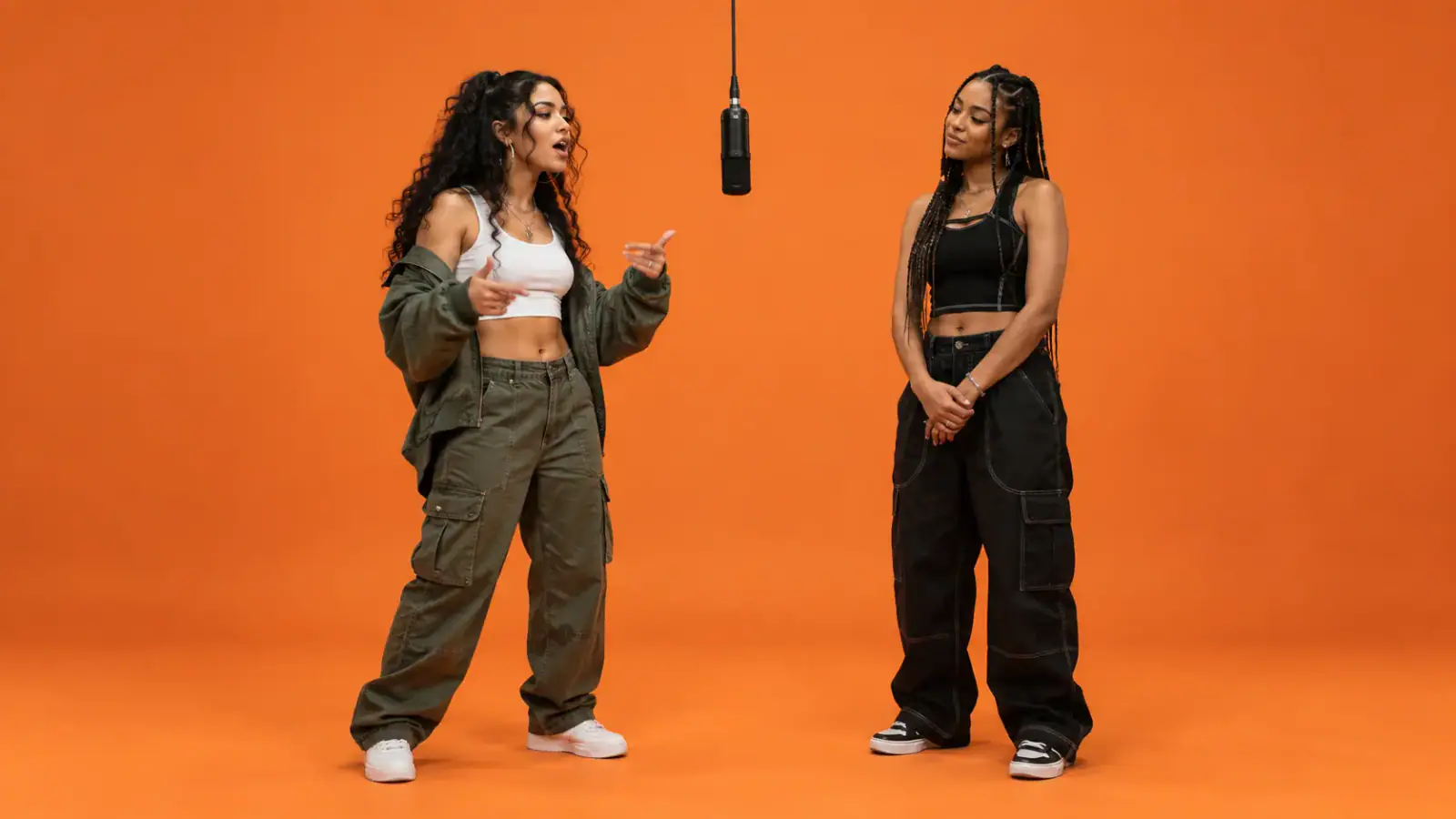 Two distinct performers placed apart in an orange booth to preserve separate identities